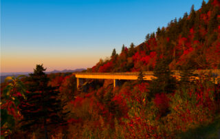 Fall's brilliant red leaves against the Blue Ridge Mountains on a sunny day with a bit of lens flare