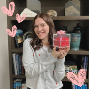 Grace Brown holding a candy jar filled with Red Hots for the Valentine's Day contest